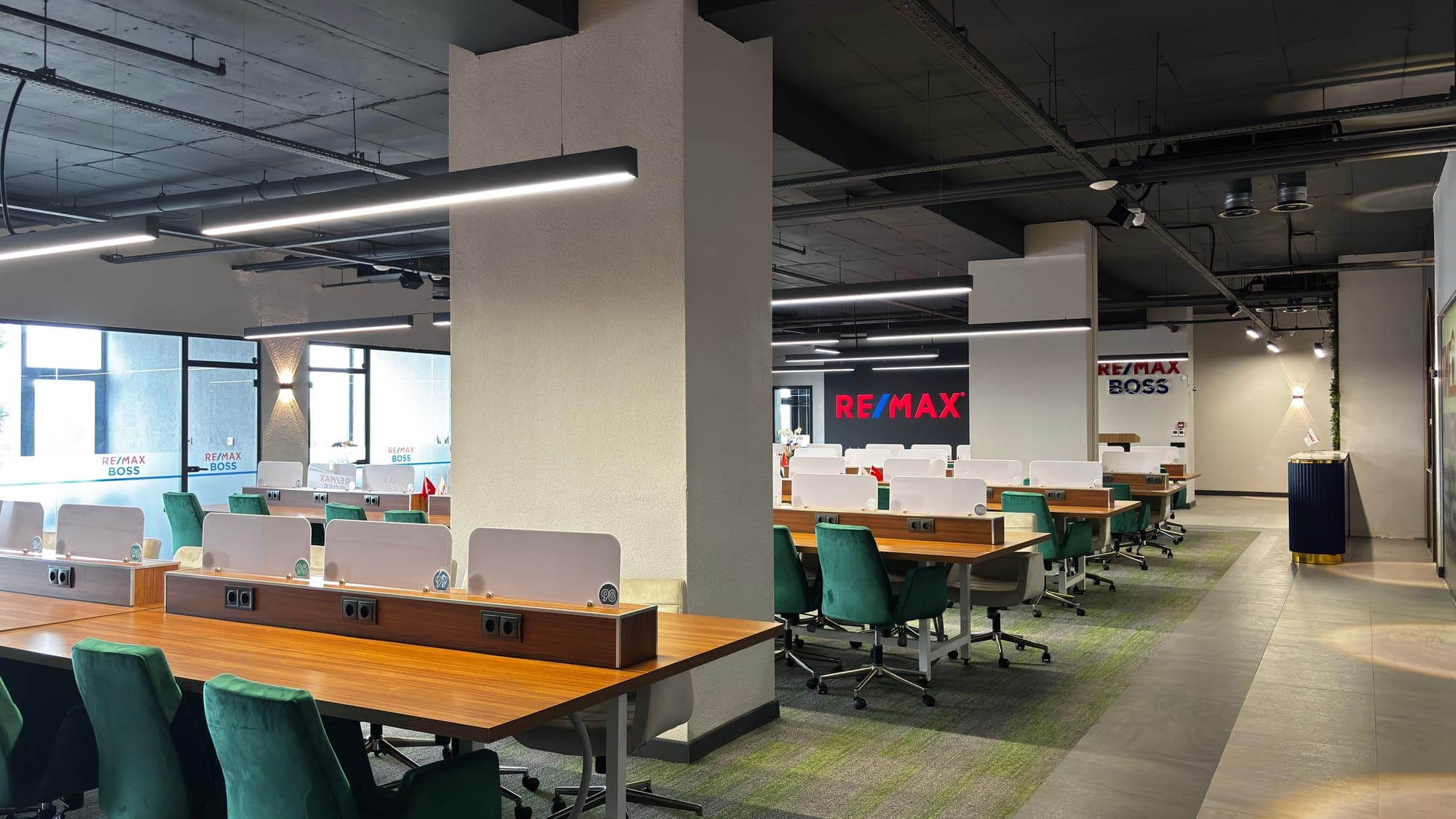 RE/MAX BOSS açık ofis alanı — yeşil sandalyeler