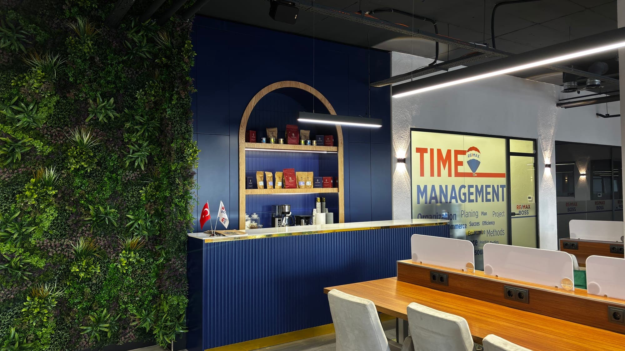 RE/MAX BOSS kahve lounge — navy bar ve bitki duvarı