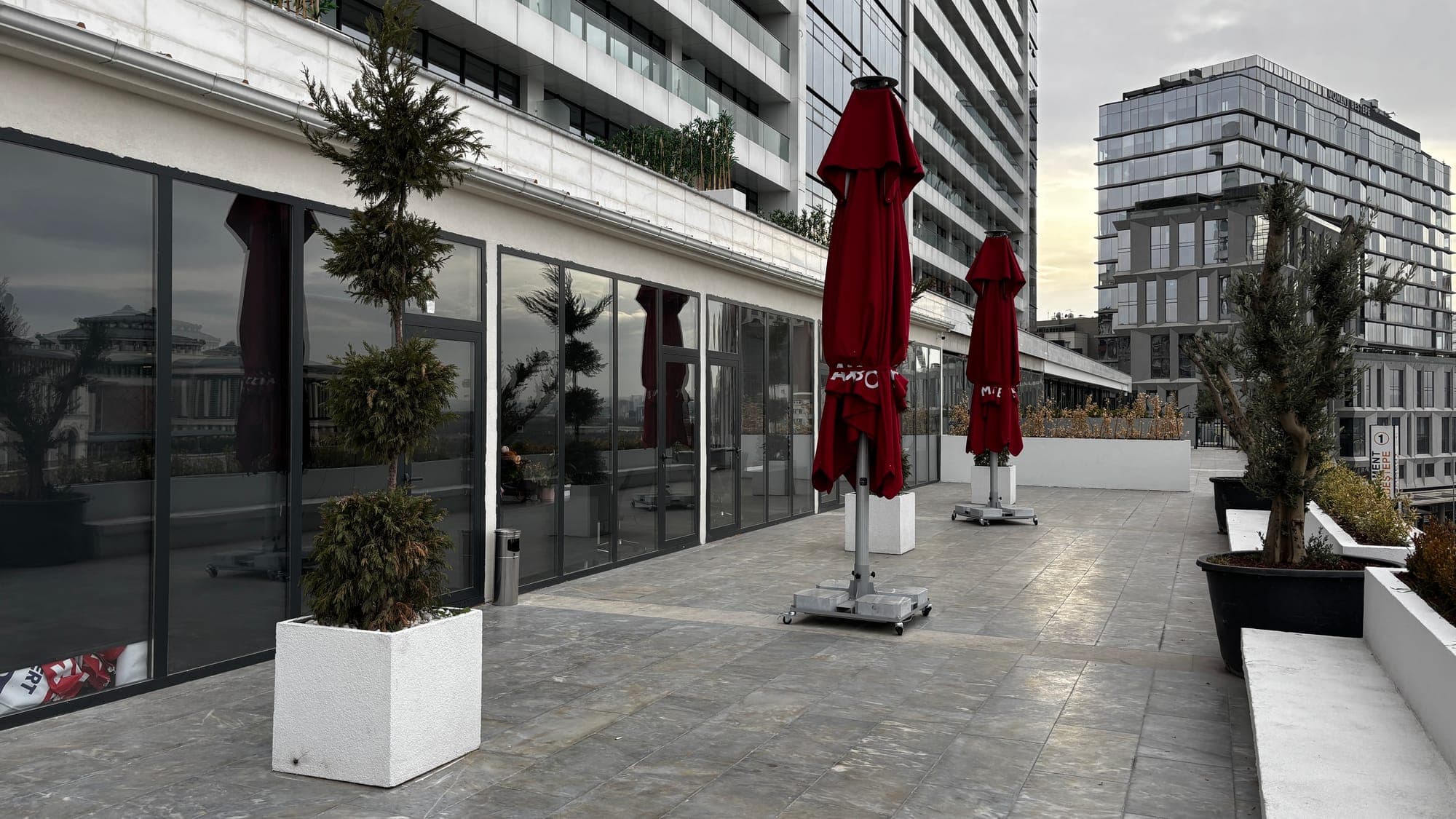 RE/MAX BOSS teras — şehir manzarası ve kırmızı şemsiyeler